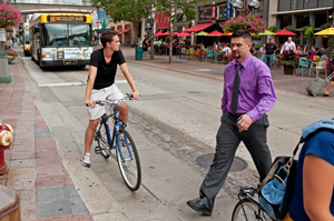 Photo of intersection with bicycle, bus and pedestrian.
